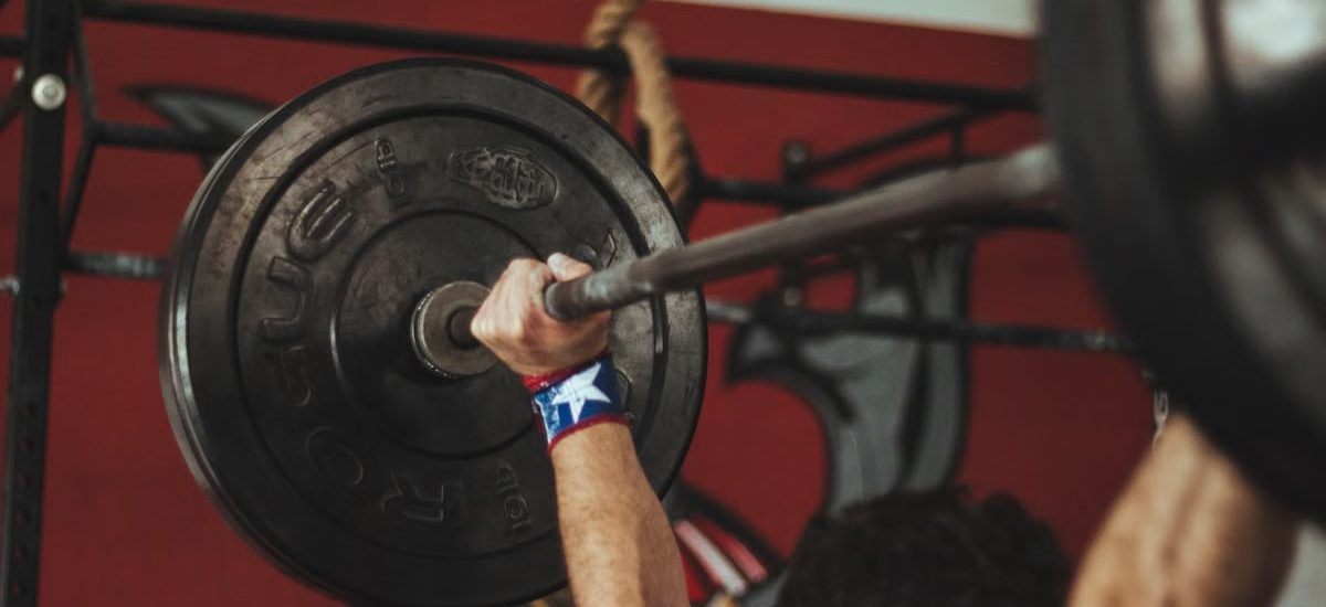 Athlete lifting heavy barbell during strength training session in gym.