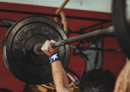 Athlete lifting heavy barbell during strength training session in gym.